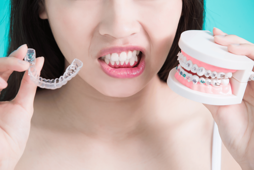 Kvinne som holder invisalign skinne og modell med tradisjonell tannregulering